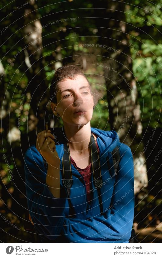 Entspannte junge Wanderin, die im Wald einen Joint raucht Wanderer Rauch Gelenk Frau Unkraut Tourist ruhen Marihuana Medikament Sommer hoch stumpf Cannabis