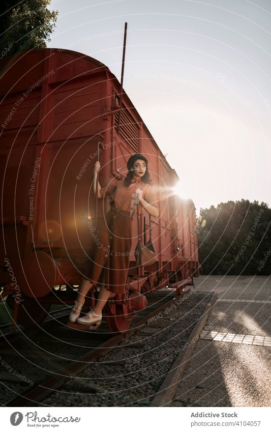 Frau in Terrakotta-Kleidung hält Handlauf eines Terrakotta-Autozuges altehrwürdig Stil Geländer Zug kokett Baskenmütze Beteiligung Stehen Blick Schritt Mode