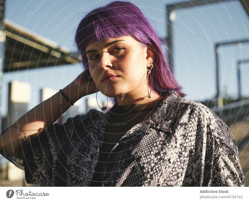 Frau mit violettem Haar schaut in die Kamera stylisch urban purpur Frisur Konstruktion glänzend Struktur Revier selbstbewusst Mode jung Stil Model Straße