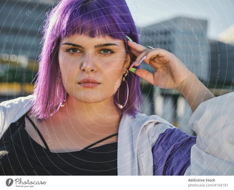 Frau mit violettem Haar lehnt an Metallzaun Lehnen berührend stylisch urban purpur Frisur Jacke glänzend Zaun Revier selbstbewusst Mode jung Stil Model Straße