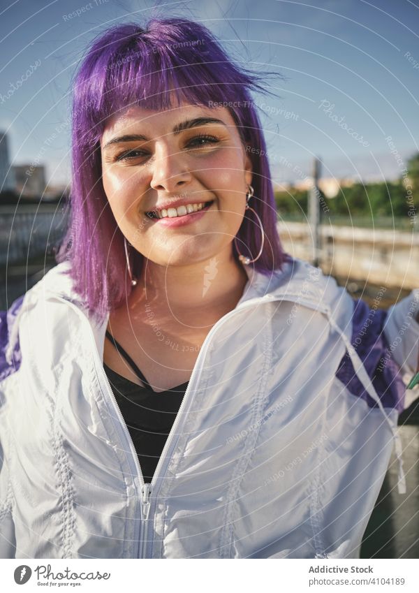 Frau mit violettem Haar lehnt an Metallzaun stylisch urban purpur Frisur Jacke Revier selbstbewusst Mode jung Stil Model Straße menschlich Außenseite Outfit
