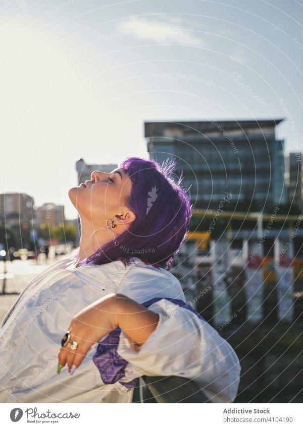Frau mit violettem Haar lehnt an Metallzaun Lehnen stylisch urban purpur Frisur Jacke glänzend Zaun Revier selbstbewusst Mode jung Stil Model Straße menschlich