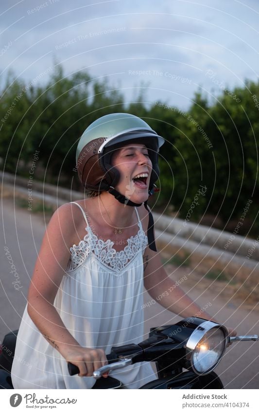 Glückliche Frau fährt Motorrad Reiten Fahrrad reisen Urlaub Freiheit grün Pflanze Baum Himmel Schutzhelm Himmel (Jenseits) Straße Lächeln Lifestyle Lachen