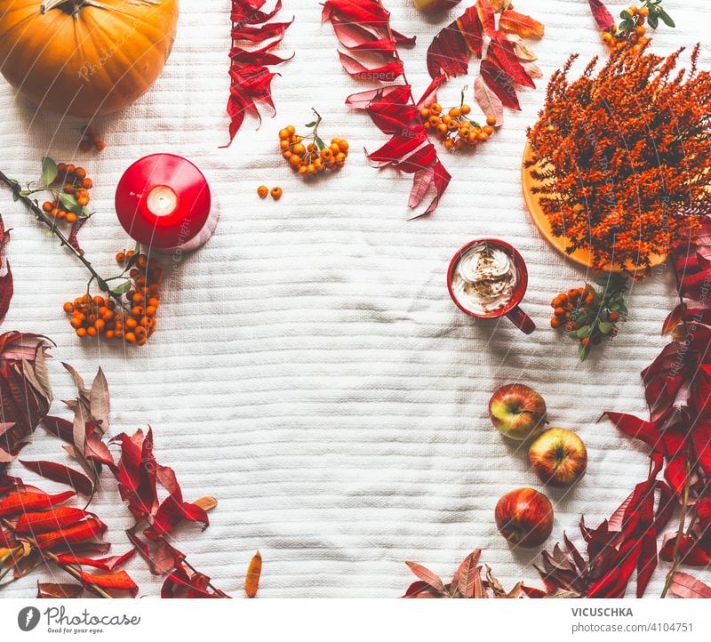 Herbstrahmen mit Kürbissen, roten Herbstblättern, Cappuccino, Kerzen und Äpfeln auf weißer Decke. Ansicht von oben. Flach legen Rahmen gemacht Herbstlaub