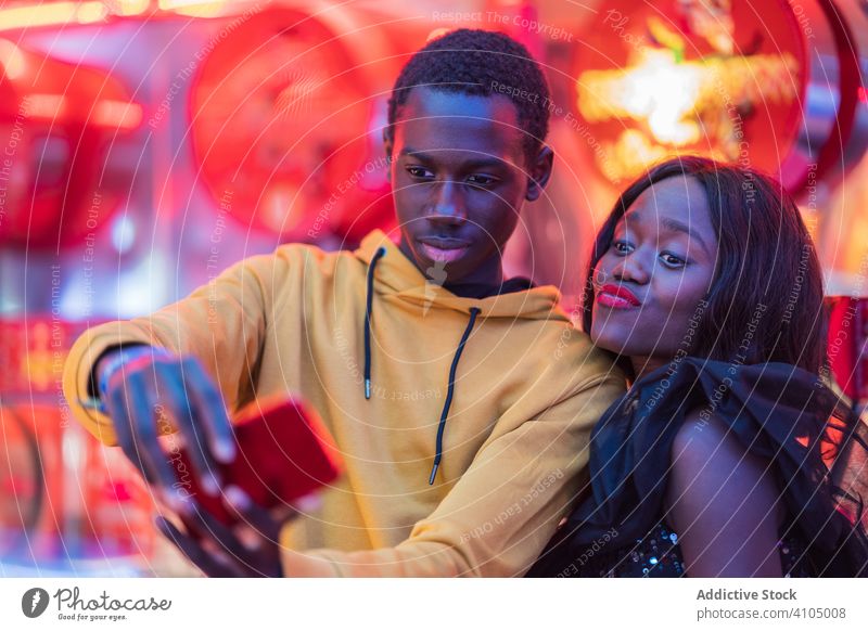 Schwarzes Paar macht Selfie auf dem Rummelplatz Messegelände Lächeln Smartphone ethnisch Nacht farbenfroh Illumination Entertainment Mann Frau Spaß Freund