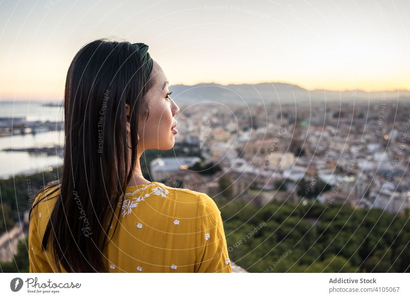 Ethnischer Tourist vor Stadt und Sonnenuntergangshimmel Frau Großstadt Tourismus Lächeln MEER Himmel ethnisch Castillo Gibralfaro Malaga Spanien Ruine reisen
