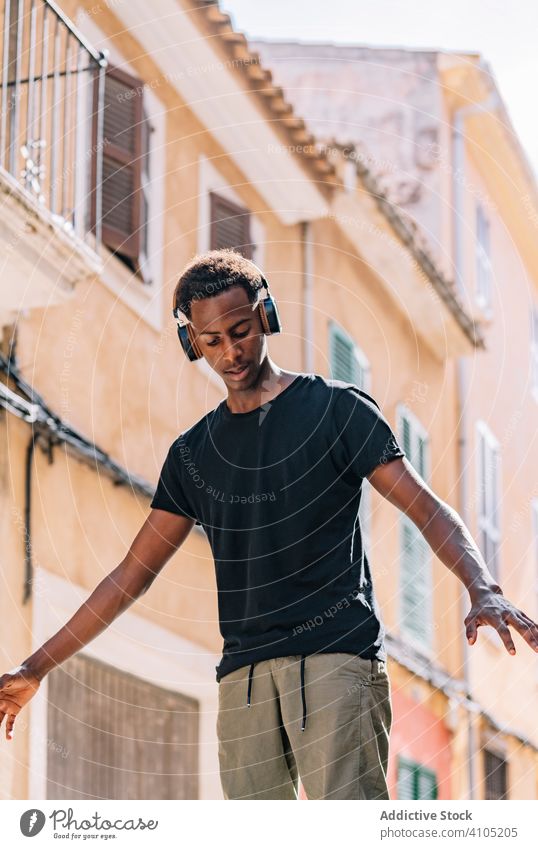 Konzentrierter junger schwarzer Mann, der auf der Straße Musik hört Hipster zuhören Kopfhörer Lifestyle Schüler sich[Akk] entspannen Entertainment Gesang