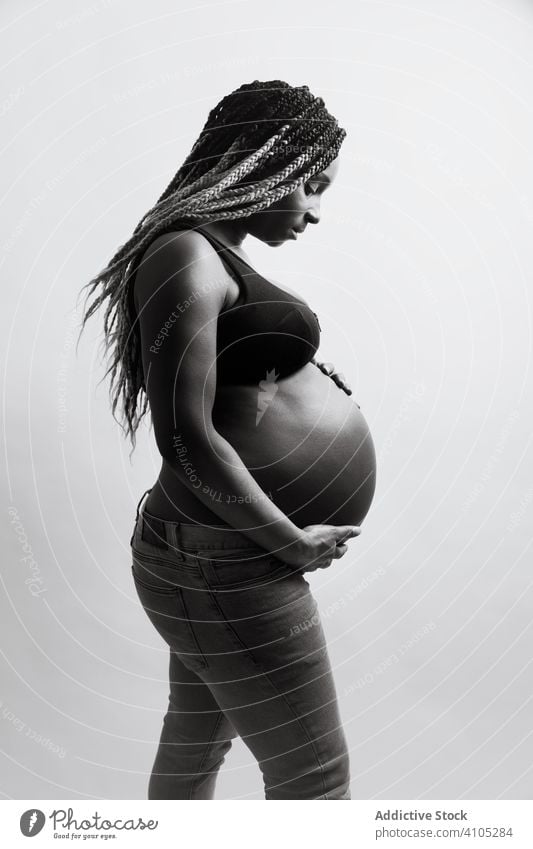 Glückliche schwangere afroamerikanische Frau hält Hände auf dem Bauch berührend heiter erwartend Mutterschaft Schwangerschaft Baby Kinderkriegen Vorfreude Liebe