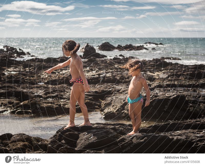 Schwestern auf Steinen am Meer MEER Ufer Zeigen Resort sonnig tagsüber Mädchen Sommer Zusammensein Geschwisterkind Kind Familie Frauenunterhose Barfuß zeigen