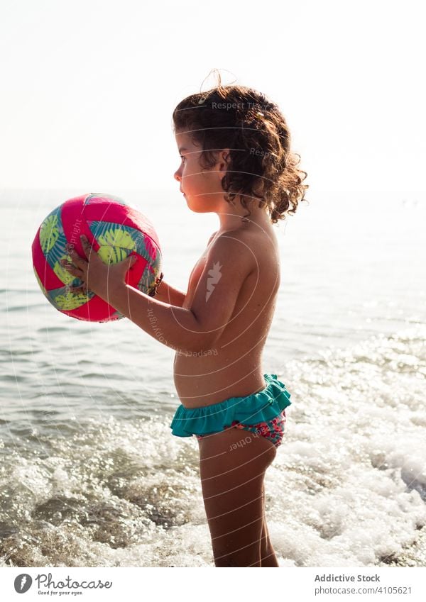 Kleines Mädchen am Strand mit einem Ball spielen Sand MEER sitzen Lenden Kind Sommer Urlaub Saison Meer Wasser Lifestyle ruhen sich[Akk] entspannen Ufer Küste