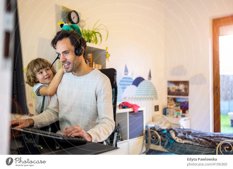 Junger Mann arbeitet von zu Hause aus mit seinem kleinen Sohn als Firma alleinerziehender Vater arbeiten Arbeiten zu Hause Computer beschäftigt Laptop
