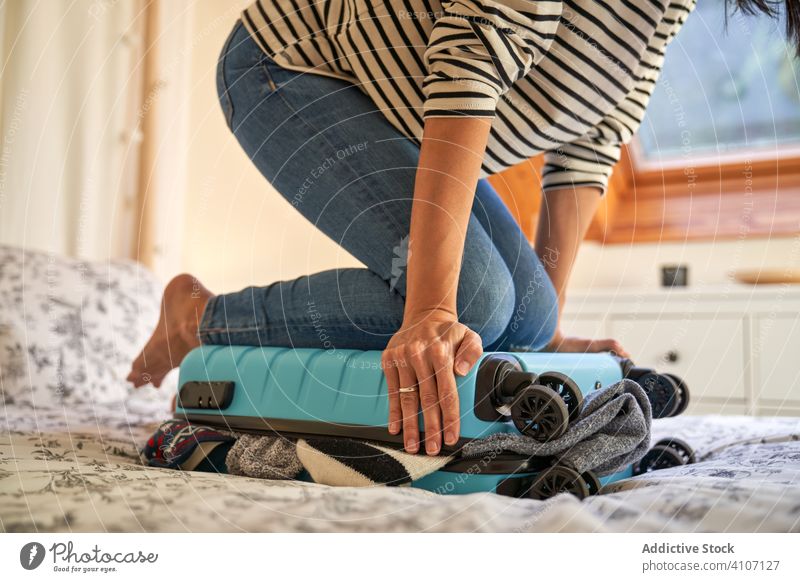 Crop-Frau schließt Gepäck im Schlafzimmer Rudel schließen reisen gemütlich heimwärts Urlaub Vorbereitung lässig Feiertag Sommer Saison Reise Koffer Barfuß