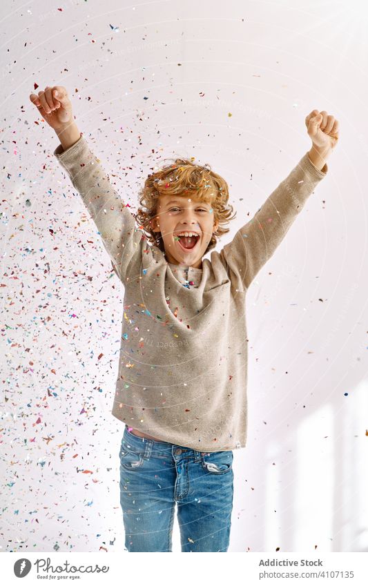Überglücklicher Junge hat zu Hause Spaß mit Konfetti spielen werfen Kind männlich Teenager farbenfroh Lächeln genießen Lachen modern Kindheit Lifestyle feiern