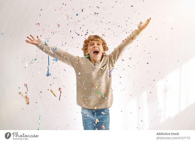 Überglücklicher Junge hat zu Hause Spaß mit Konfetti spielen werfen Kind männlich Teenager farbenfroh Lächeln genießen Lachen modern Kindheit Lifestyle feiern