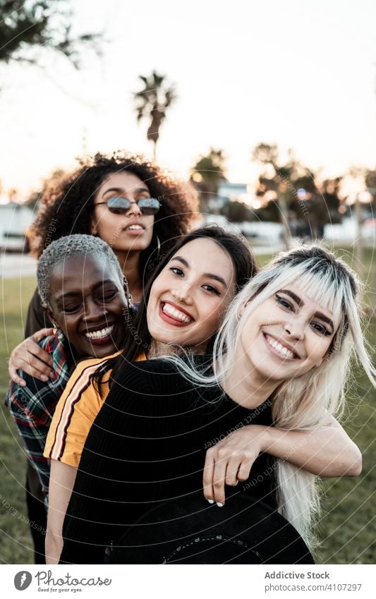 Multiethnische Gruppe von weiblichen Hipsterinnen, die mit jeder einzelnen kuscheln Menschengruppe Frauen Kuscheln jung Stil Lächeln Umarmung Porträt