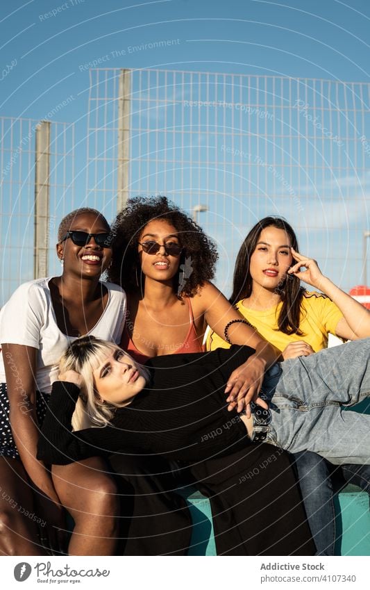 Fröhliche junge multirassische Freundinnen genießen ihre Freizeit auf der Straße Frau Spaß Zusammensein Sitzung Stadion Schüler Zeitvertreib Lifestyle