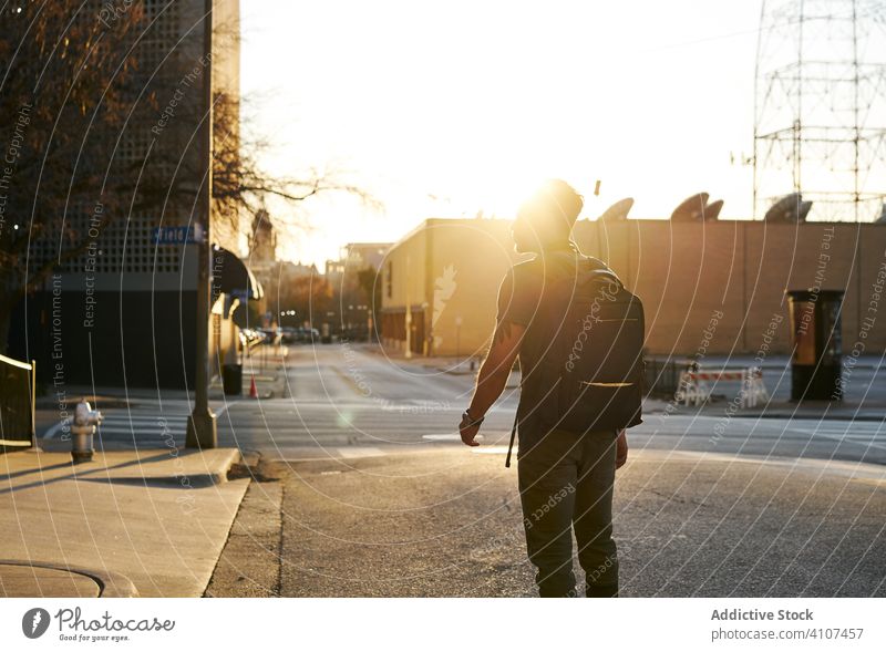 Anonymer Mann, der bei Sonnenuntergang auf der Straße geht laufen Großstadt lässig jung genießen Outfit Rucksack Zeitgenosse stylisch Lifestyle modern ethnisch