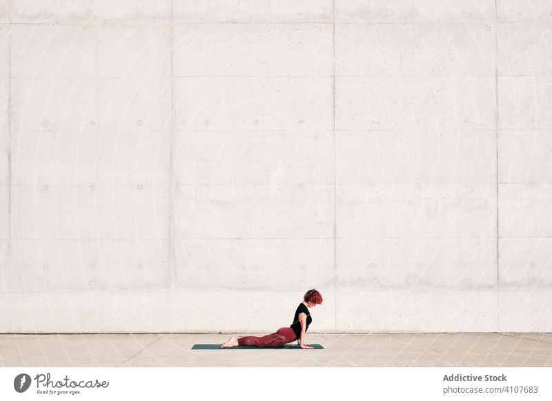 Schlanke, konzentrierte Frau übt Yoga in Sphinx-Pose auf der Straße Dehnung üben Asana Training Übung Baby-Kobra-Pose beweglich Athlet Windstille gymnastisch