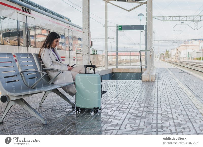 Frau wartet auf Zug und telefoniert Station Handy reisen benutzend Smartphone Feiertag Koffer Eisenbahn Bank jung Verkehr Terminal Transport Ausflug warten