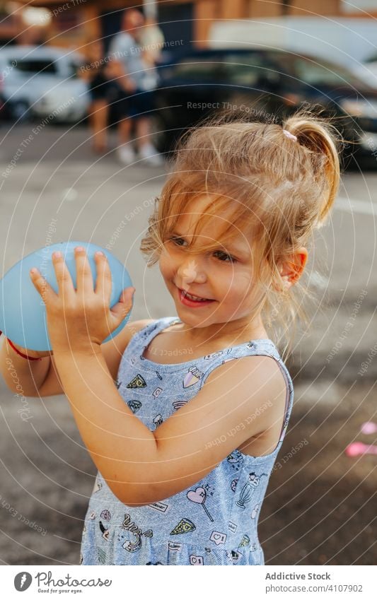 Mädchen mit Wasserballon auf der Straße Luftballon Bürgersteig Sommer Wasserbombe spielen Stadt sonnig tagsüber Kind Großstadt Straßenbelag Spielzeug niedlich