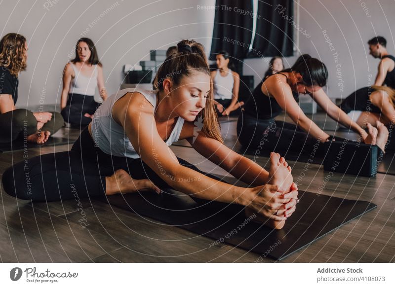 Fit weiblichen Athleten Stretching Beine in janu sirsasana Position beim Üben von Yoga in modernen Studio Training Übung beweglich Fitness üben Janu Sirsasana