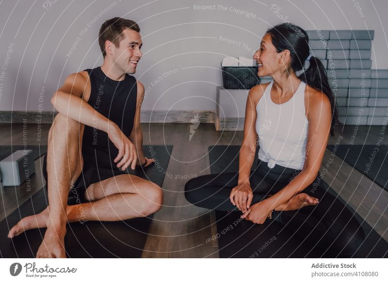 Fröhliche Freunde führen ein interessantes Gespräch während einer Trainingspause in einem modernen Fitnessstudio Yoga Pause Unterlage üben sich[Akk] entspannen