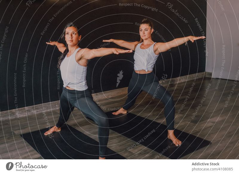 Frauen dehnen ihren Körper und üben Yoga in Kriegerpose Trainerin Krieger-Pose Übung Gleichgewicht Dehnung Unterlage Klasse Lektion Training Zusammensein Asana