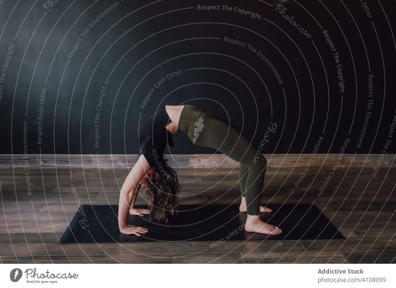 Frau streckt Körper in Radstellung in einer Matte in einem Studio Yoga Dehnung Unterlage Training üben beweglich gymnastisch urdhva dhanurasana positionieren