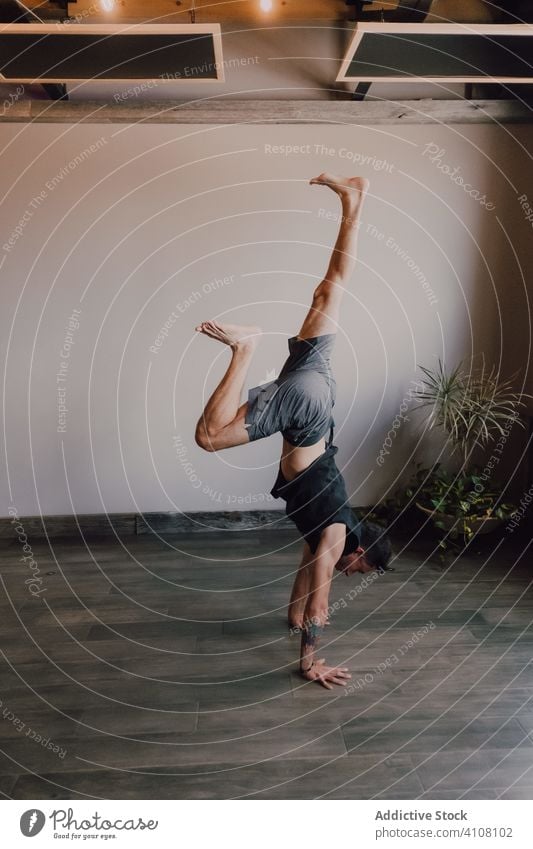 Sportler übt Yoga im Handstand in einem modernen Studio Mann gymnastisch sportlich üben auf den Kopf gestellt nach unten gerichtete Hundehaltung professionell
