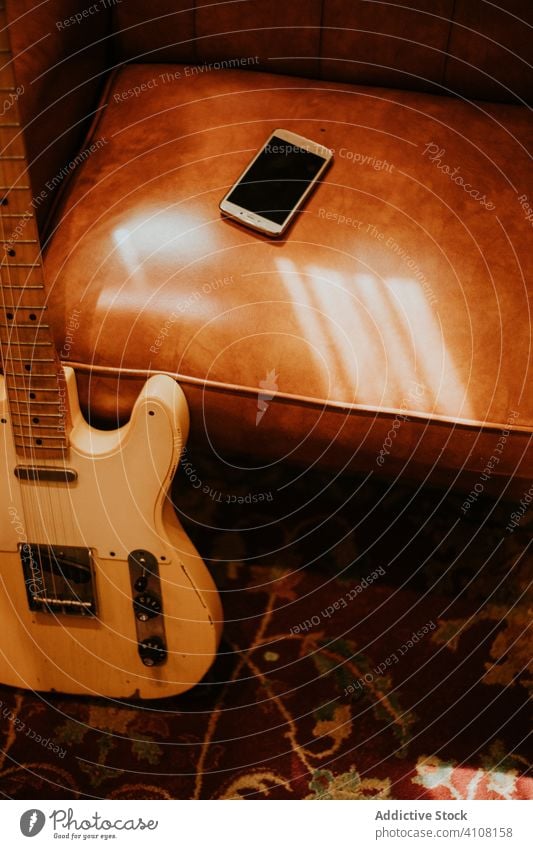 Gitarre auf Sofa gelehnt mit Smartphone im Zimmer Raum benutzend alt Instrument Musik Klang Apparatur unterhalten Melodie akustisch Felsen klassisch