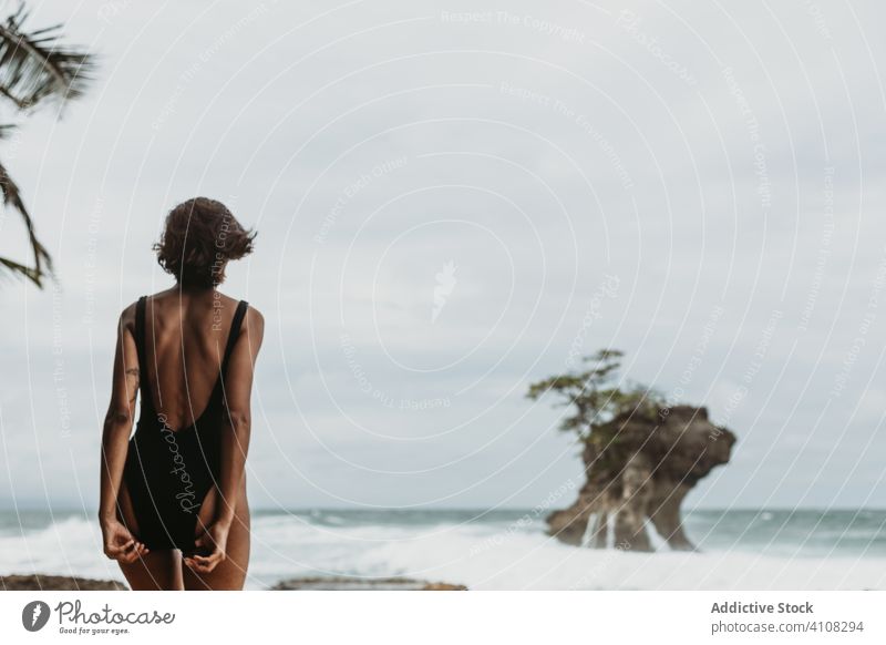 Unerkennbare weibliche Reisende in Badekleidung am einsamen Meeresstrand Frau Strand Unwetter tropisch Wind reisen Meeresufer sorgenfrei Freiheit Gezeiten