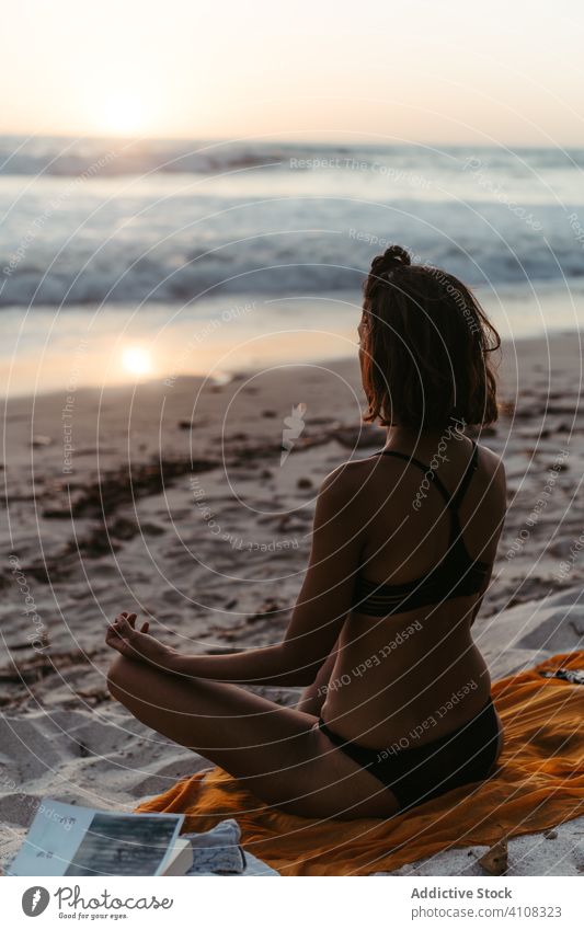 Unbekannte Frau meditiert am Strand bei Sonnenuntergang meditieren üben Yoga Lotus-Pose Sprit Asana Körperhaltung Gelassenheit Lifestyle sich[Akk] entspannen