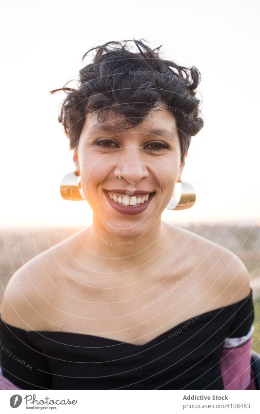 Zeitgenössischer ethnischer weiblicher Hipster mit strahlendem Lächeln Frau Teenager modern Glück Porträt Individualität Stil informell Piercing Natur aufgeregt