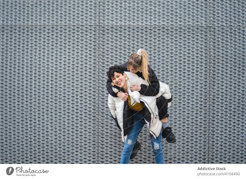 Zeitgenössische weibliche Teenager, die zusammen Spaß haben Frauen Freund Huckepack Glück Lachen urban trendy Hipster Lächeln genießen Großstadt Straße Wand