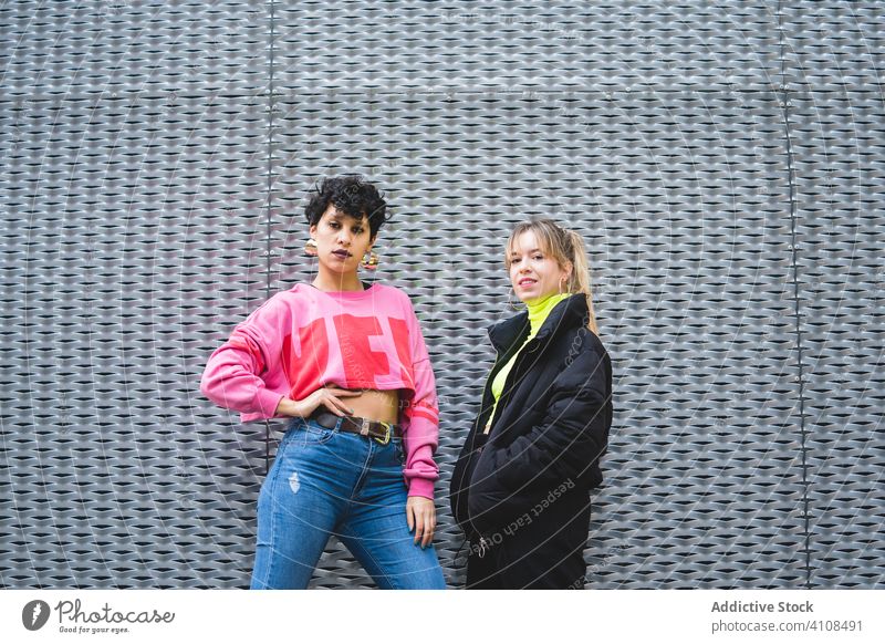 Zufriedenes multiethnisches weibliches Paar in trendiger Kleidung auf der Straße in der Stadt Freundin Teenager cool trendy farbenfroh selbstbewusst lesbisch