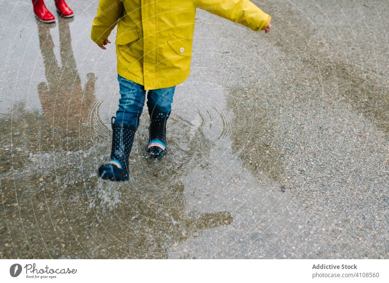 Anonyme lustige Kinder spielen in einer Pfütze im Park Allee Spielen unordentlich Wetter Zusammensein Geschwister Saison Wasser nass Schmutz Kindheit Schlamm