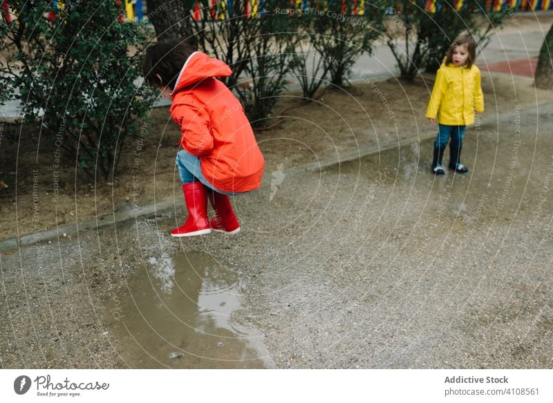 Lustige Kinder spielen in Pfütze im Park Gasse Spielen unordentlich Wetter Zusammensein Geschwister Saison lustig Wasser nass Schmutz Kindheit Schlamm Herbst