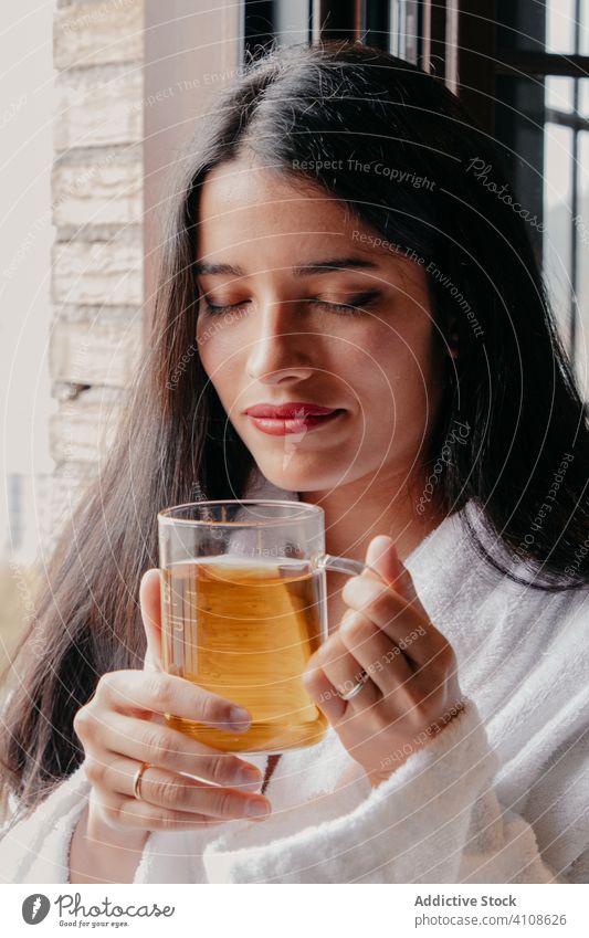 Entspannte Frau im Bademantel genießt Tee sich[Akk] entspannen ruhen trinken Morgen Fenster Becher gemütlich lässig Getränk Tasse Glas Lifestyle Dame jung