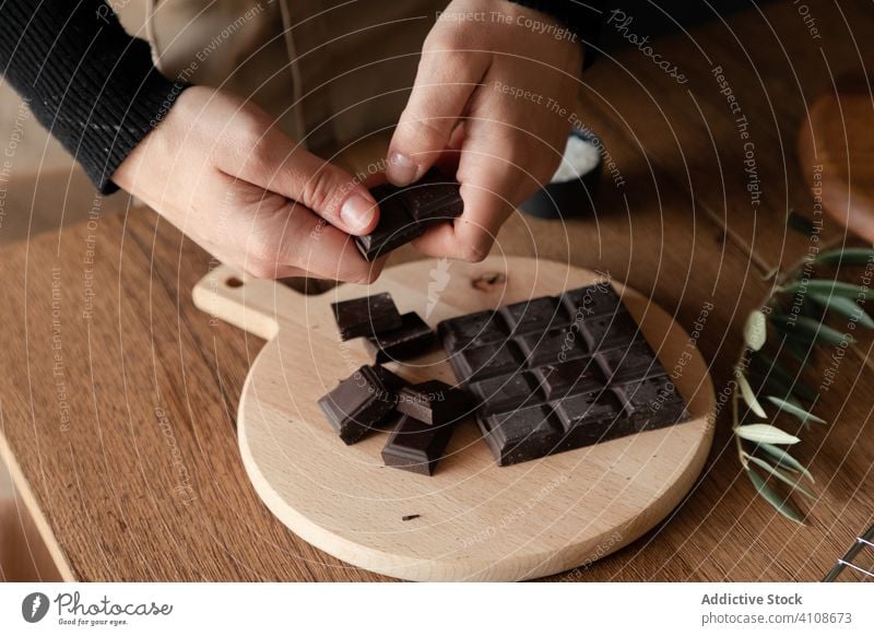 Frau zerbricht Schokoladentafel in der Küche Pause Lebensmittel vorbereiten Koch Rezept Bestandteil Tisch hölzern süß Dessert Hand Bar Prozess Spielfigur
