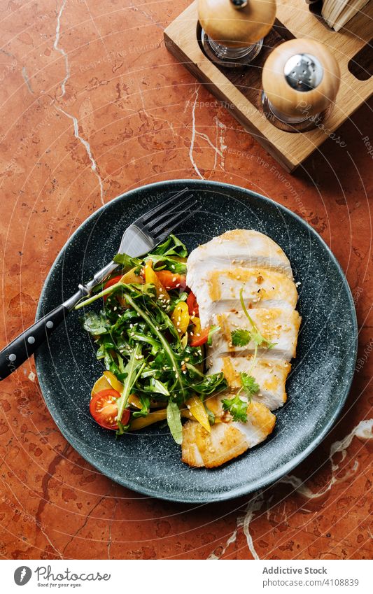 Gesunder Fisch mit Huhn und Salat im Restaurant Hähnchen Salatbeilage Fleisch Hohe Küche Filet Kraut Kirschtomaten geräuchert frisch Gesundheit Teller Speise
