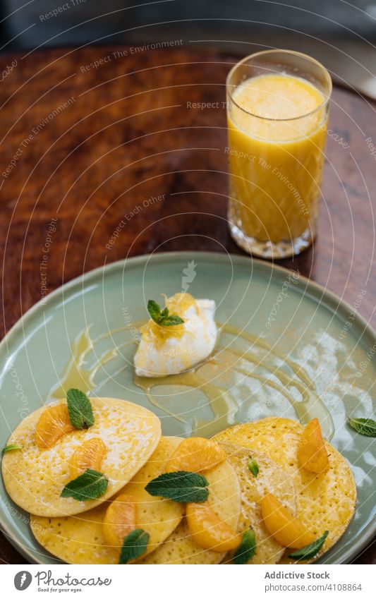 Leckeres Frühstück mit Pfannkuchen und Saft im Restaurant Haute Cuisine Scheibe Spielfigur Mandarine Saucen Belag Minze Glas farbenfroh süß Sahne Portion orange
