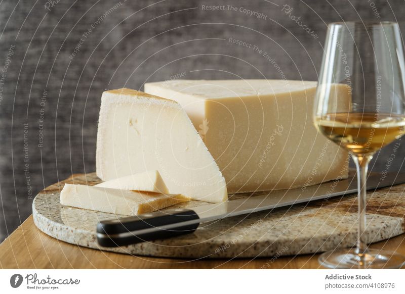 Käse auf dem Schneidebrett und Wein auf dem Tisch Messer Holzplatte Getränk Glas Feinschmecker Alkohol lecker geschmackvoll Restaurant trinken Lebensmittel