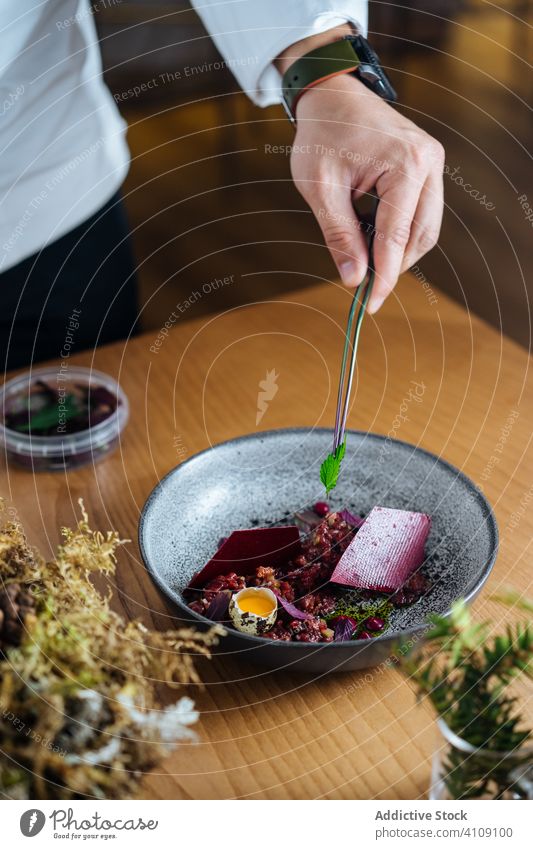Anonyme Person bereitet Salat mit Fisch und Beeren zu Salatbeilage Hering Speise Teller Preiselbeere Wachtelei roh kalt Lebensmittel Feinschmecker nordisch