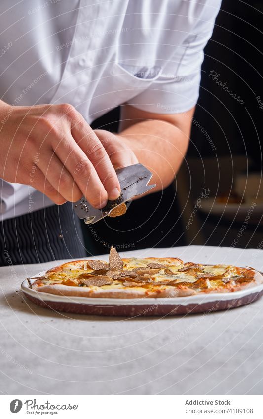 Crop-Chefkoch schneidet Trüffel auf Pizza Küchenchef Scheibe Restaurant Koch Tisch Mann Abendessen fein Lebensmittel Reichtum Speise Mahlzeit teuer