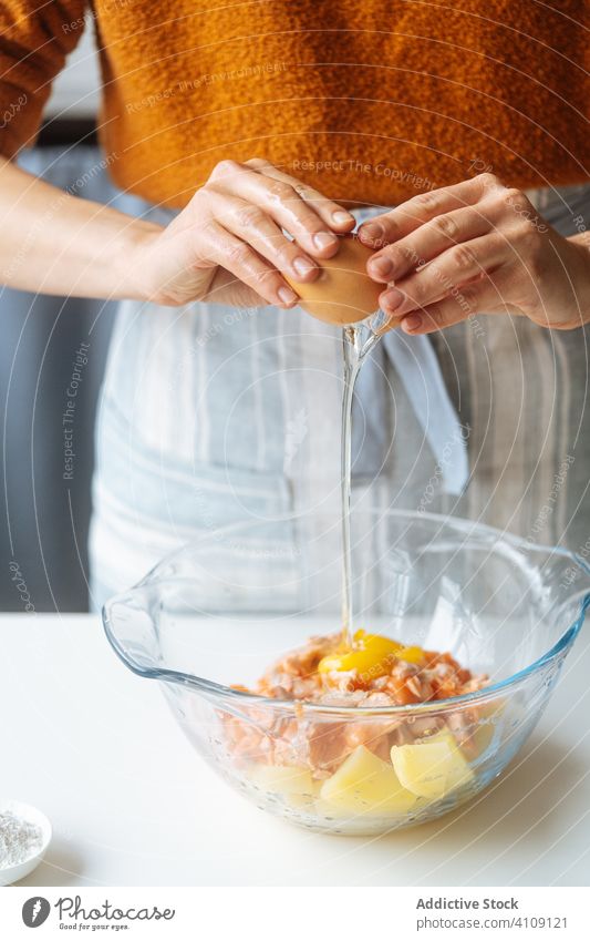 Frau gibt Ei in Schüssel mit Lebensmittelzutaten Pause Essen zubereiten Bestandteil hinzufügen mischen Füllung Rezept Fisch Lachs Kartoffel Küche