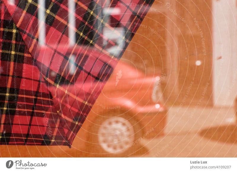 Im Schaufenster ein karierter Regenschirm, im Sonnenlicht spiegelt sich ein parkendes, rotes Auto Straße orange Reflexion & Spiegelung Tag Stadt Menschenleer