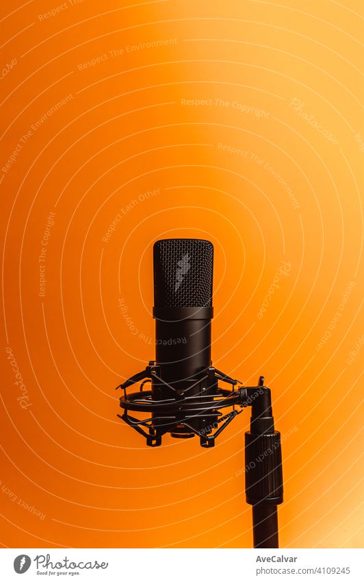 Minimalistisches Bild eines Streaming-Mikrofons über einem orangefarbenen Hintergrund mit Kopierraum, minimales Konzept, Technologie-Streaming Attrappe