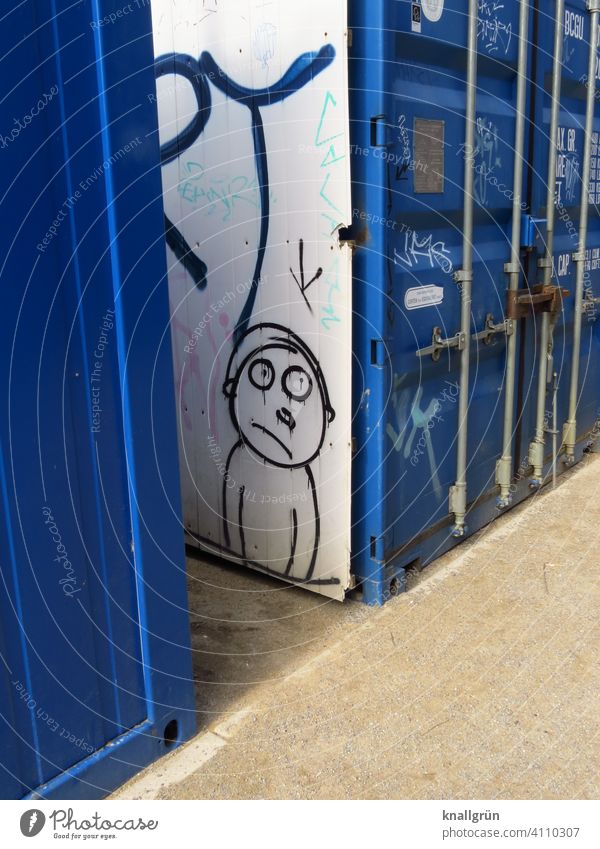 Lagercontainer mit Graffiti Strichmännchen Blick Container blau weiß Außenaufnahme Menschenleer leidend Fragender Blick große Augen Figur sandboden braun