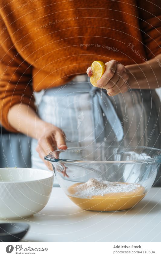 Frau presst Zitrone in eine Schüssel am Tisch aus Koch quetschend Zitrusfrüchte Püree Saft Mischung orange Glas Küche Gesundheit Lebensmittel Veganer