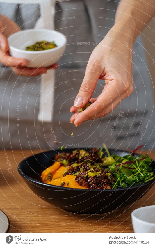 Erntearbeiter, der Samen in eine Schüssel mit Salat schüttet Person Koch Speise hinzufügen Gesundheit Veganer Küche Lebensmittel Vorbereitung heimwärts Mahlzeit